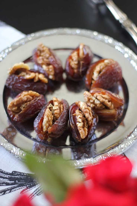 chocolate stuffed dates filled with nuts arranged on a silver plate